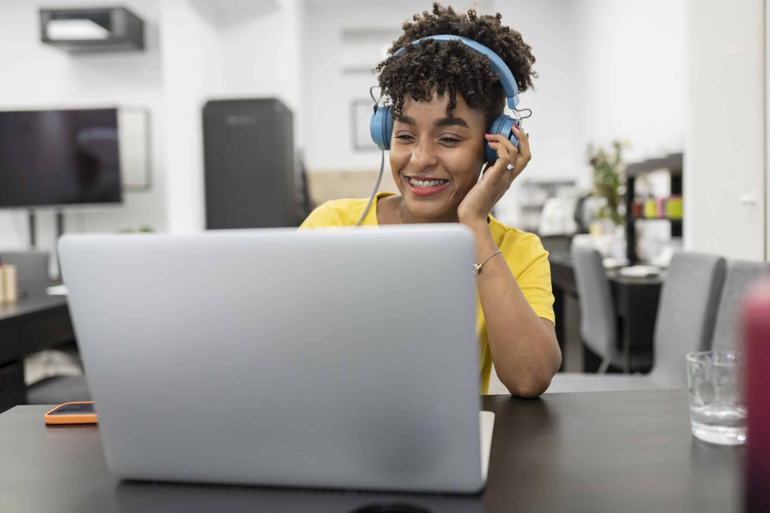 Woman with a headset on listening to a podcast on her laptop