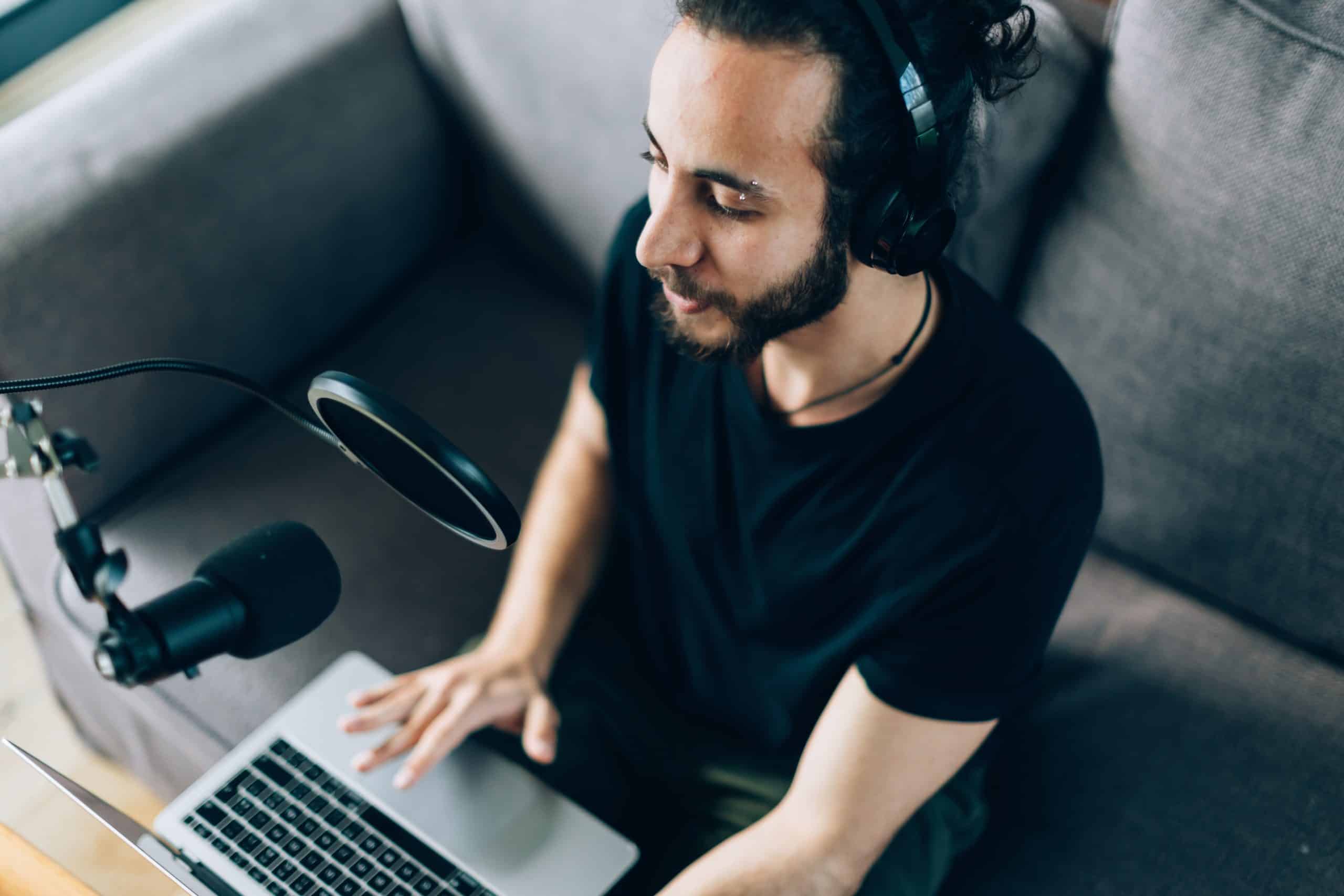 young man recording podcast on couch in home studio