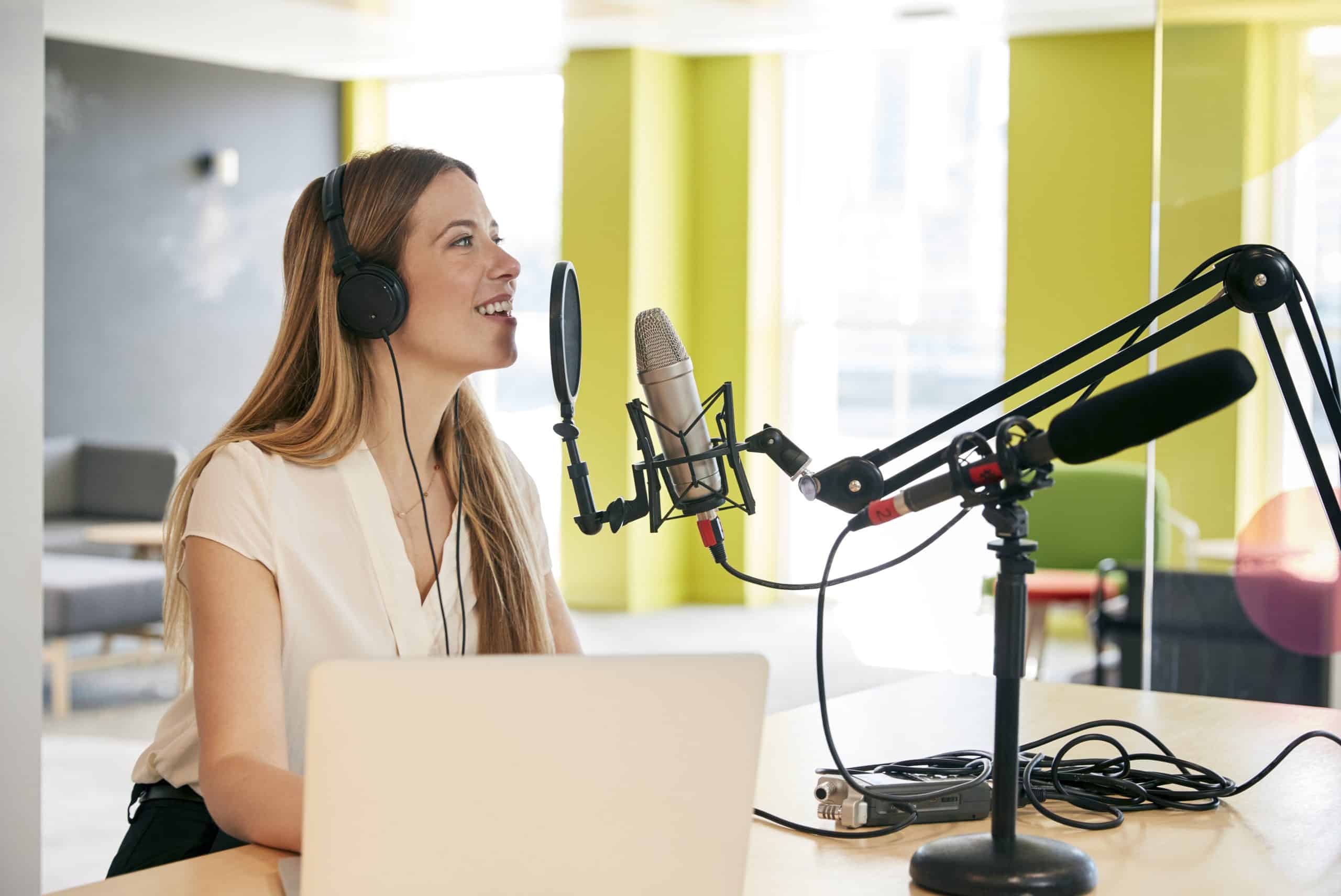 Young woman broadcasting in a studio with headphones and a microphone