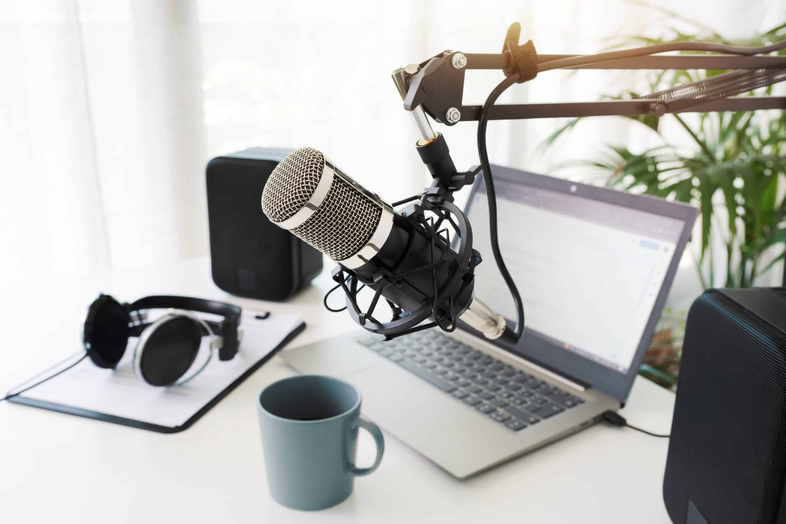 Professional microphone and headphones with a laptop and cup of coffee ready to podcast.