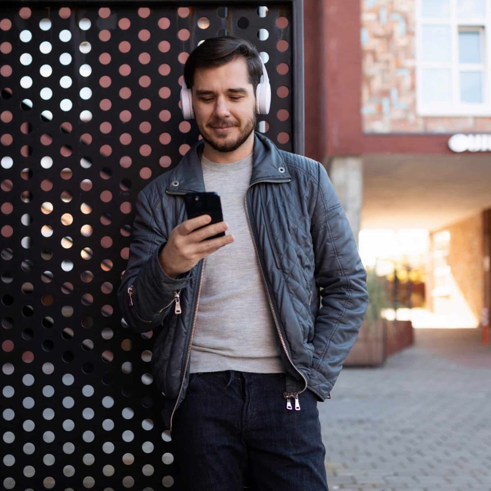 man listening to podcast on headphones while looking at phone